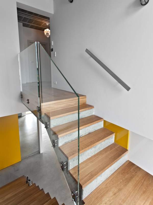 Бетонная лестница с деревянными ступенями и стеклянными перилами в частном доме