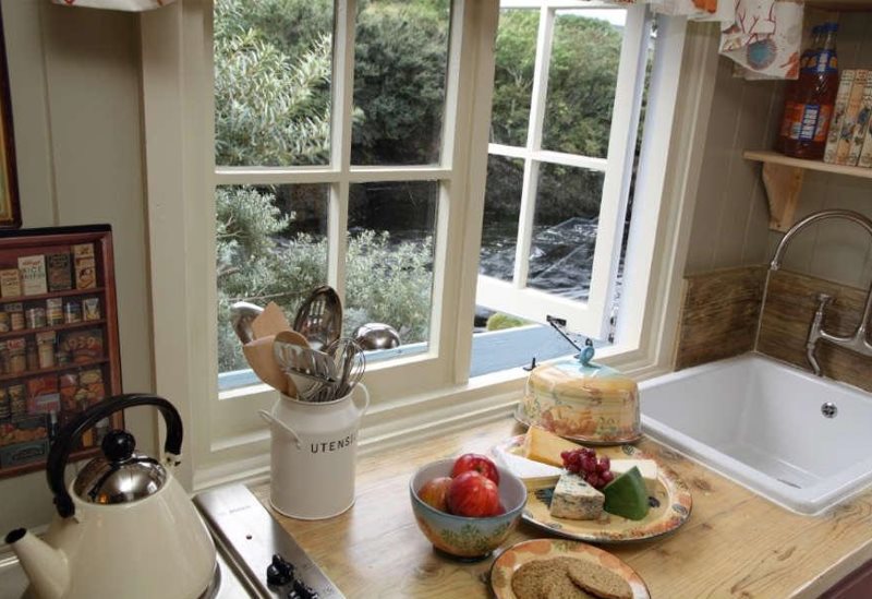 Кухонная мойка перед окном с деревянной рамой