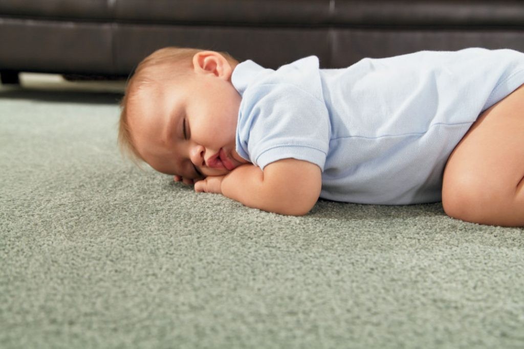 Спящий младенец на ковролине нейтрального цвета