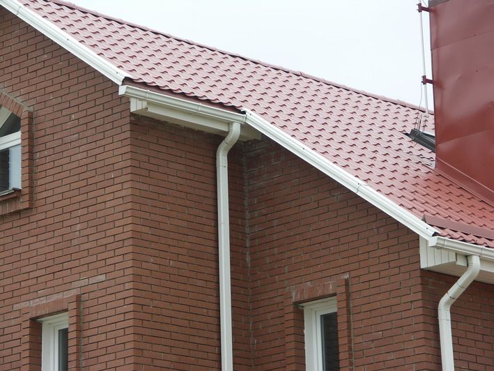 Фото: металлочерепица Металл Профиль на крыше здания, смонтированная водосточная система